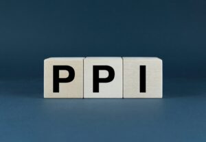 Three wooden cubes on a navy blue background, each emblazoned with a letter to spell ‘PPI’.