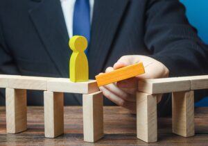 A man adds the final block to complete a bridge made out of blocks, representing bridging finance.