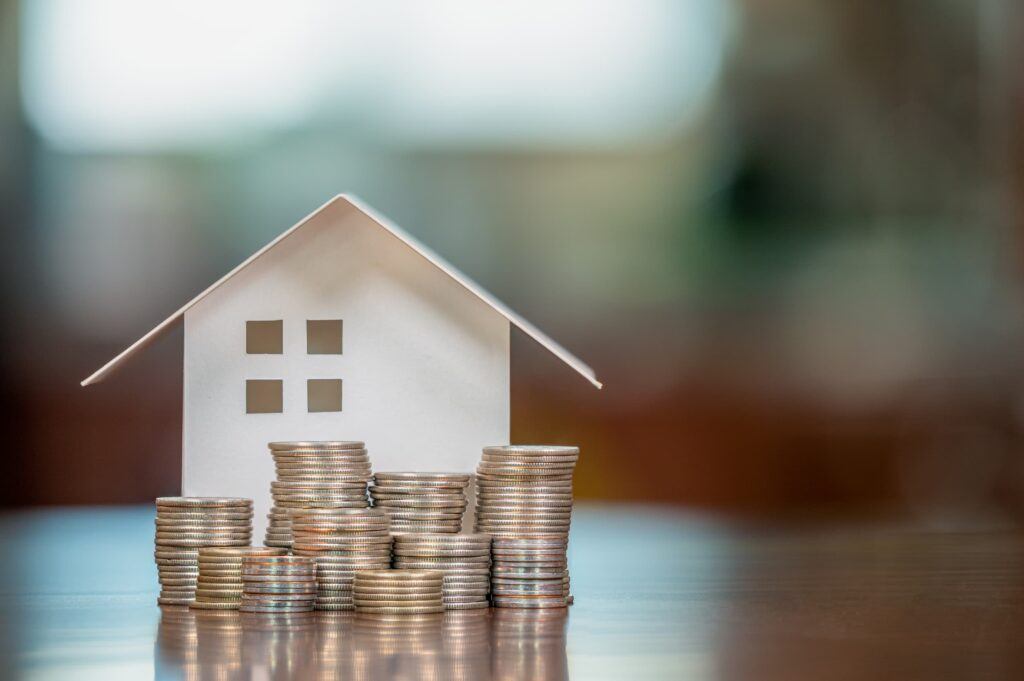 A model of a house with stacks of coins positioned in front of it.