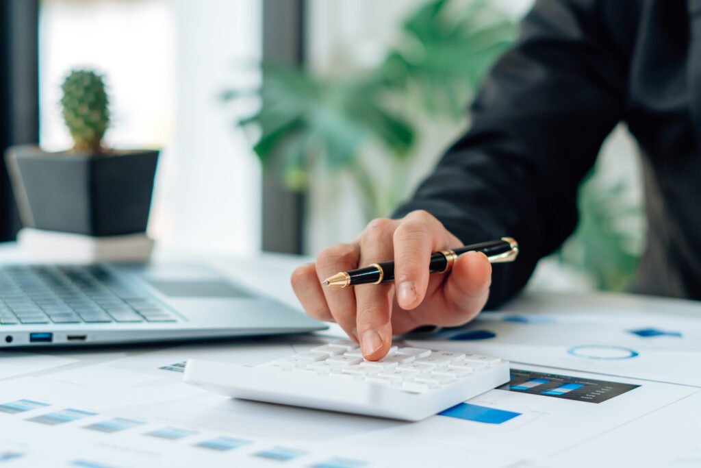 Close-up of a person in an office using a pen and calculator to work out repayments.